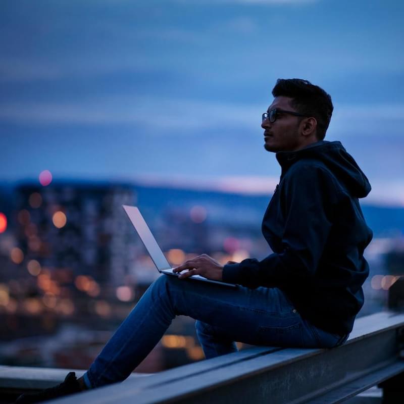 Männlicher Mitarbeitender arbeitet am Laptop bei Abenddämmerung - Mitarbeiterbefragung und Transformation